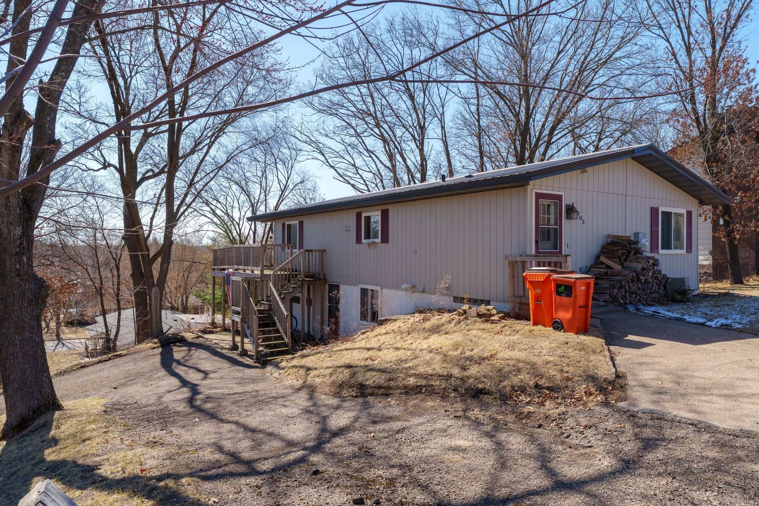 Panoramic view of a wooded backyard area with bare trees and scattered debris in winter.
