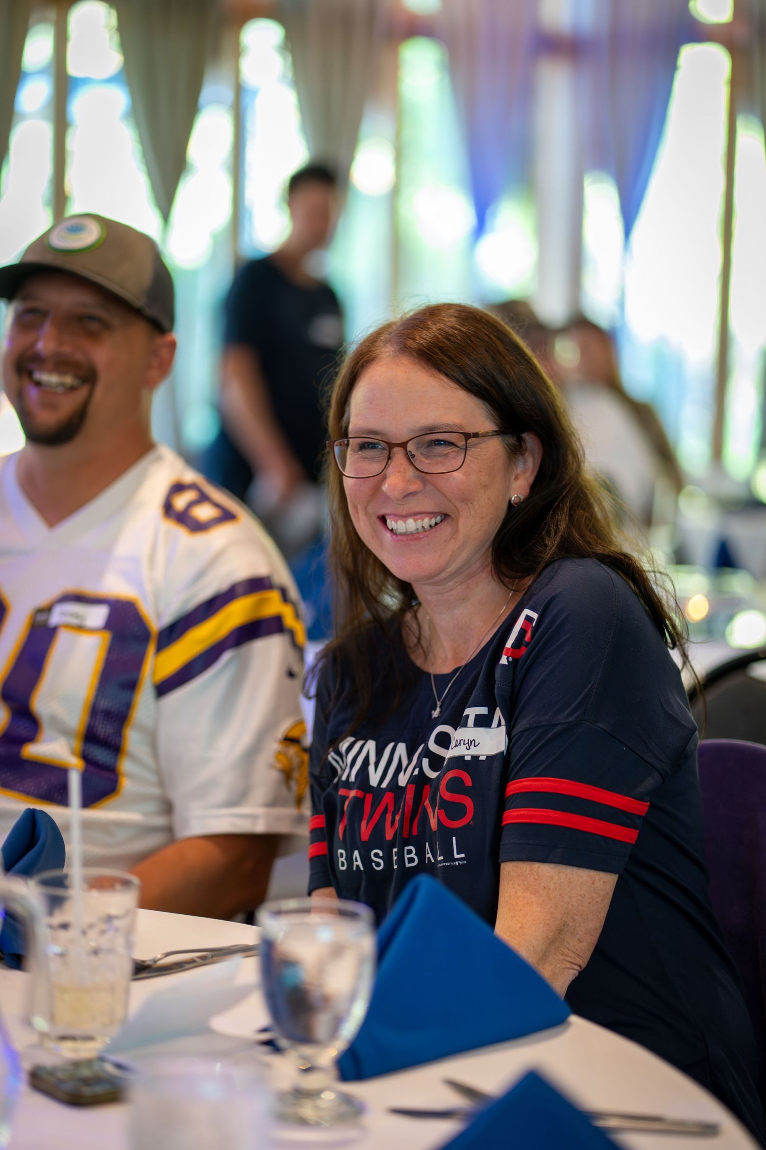 Sports fans enjoying a social gathering at a table, with Minnesota Twins baseball apparel visible in the scene.