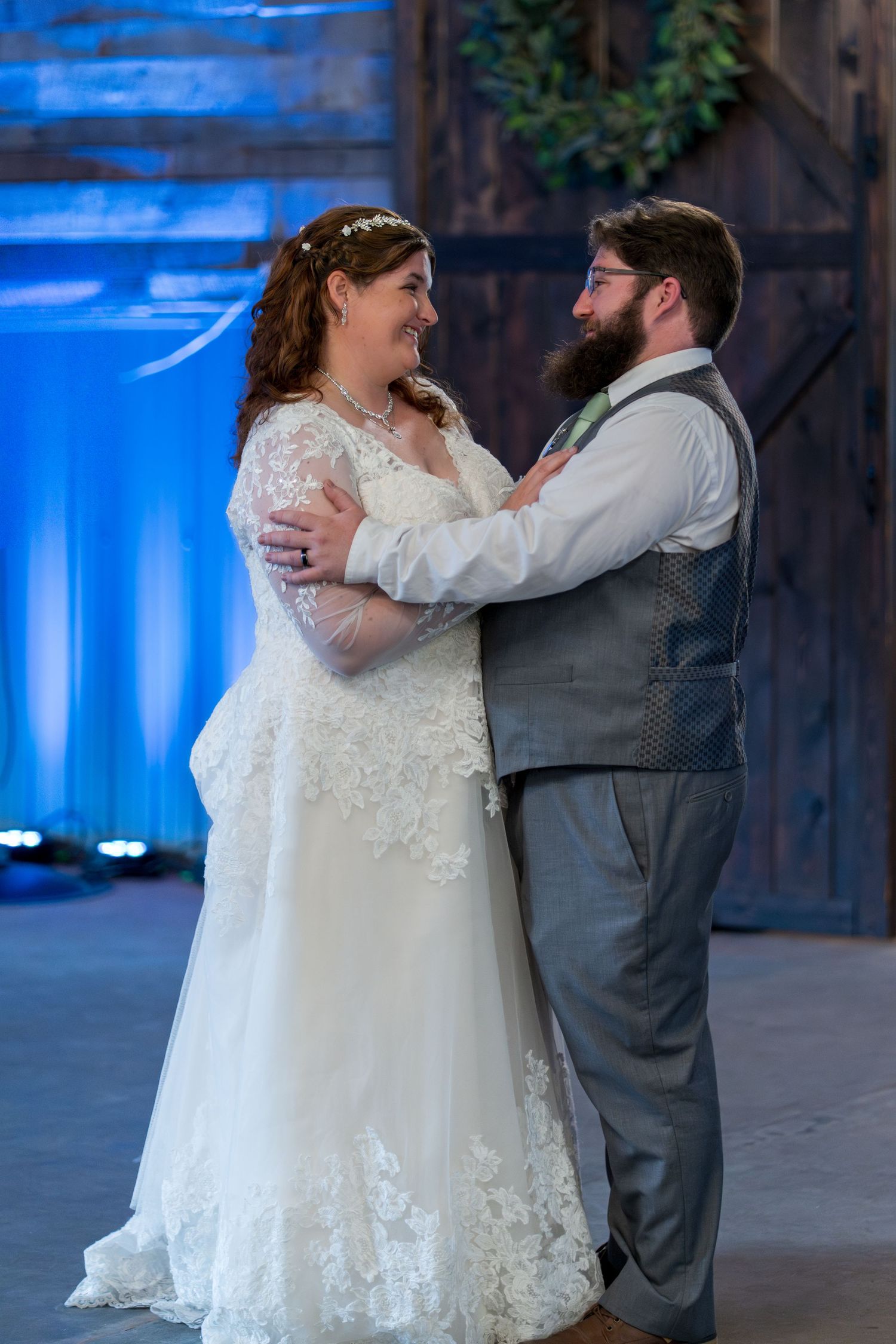 A couple shares their first dance at their wedding reception with blue lighting and elegant decor in the background.
