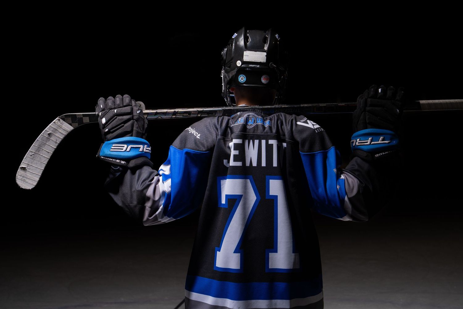 A collection of blue and black football jerseys displayed in a dark room with dramatic lighting.
