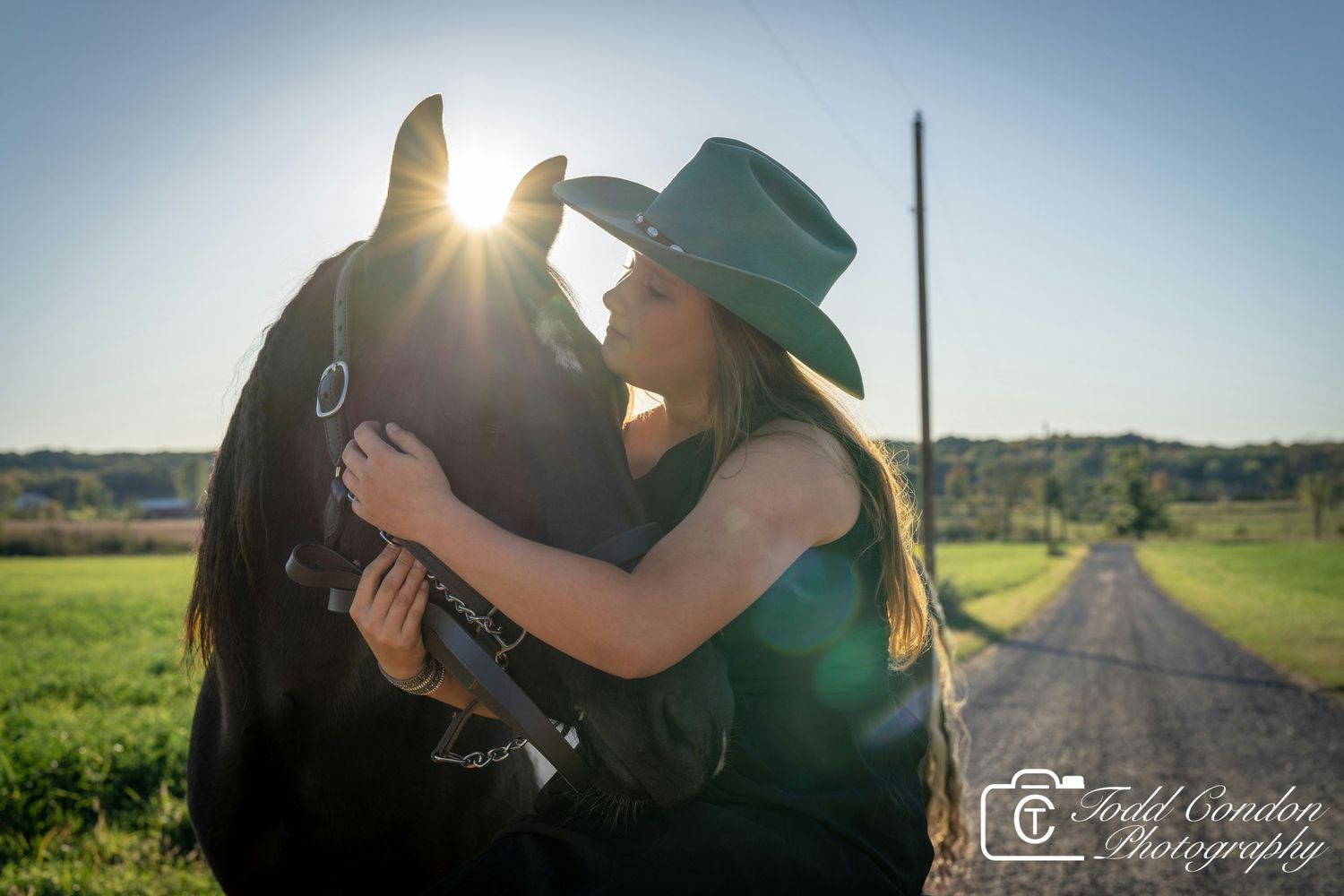 Silhouetted couple embraces in a romantic sunset moment along a rural country road.