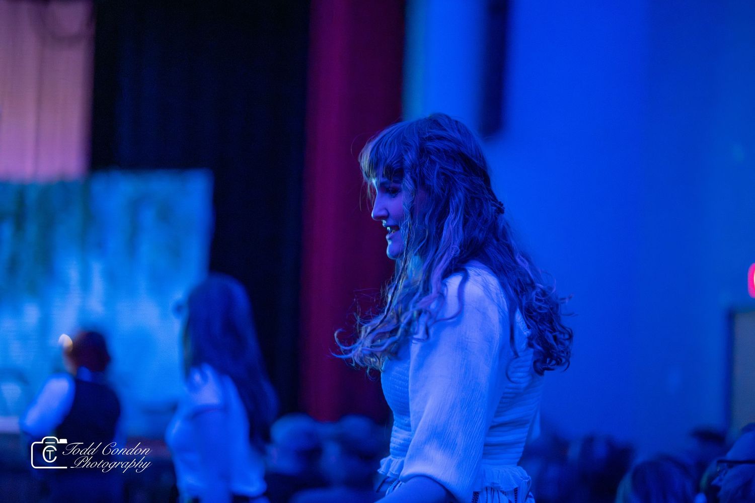 Dramatic blue stage lighting illuminates performers during a theatrical production.