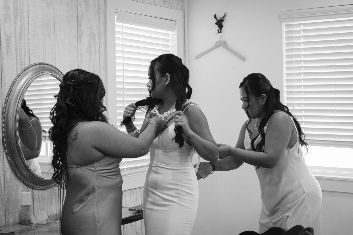 Bridesmaids helping the bride fix her laui for her wedding day.