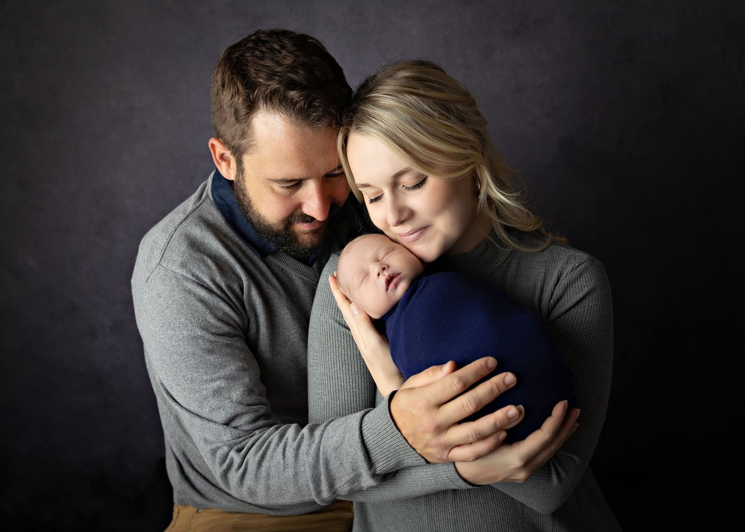 A tender black and white portrait series showing intimate moments between a couple embracing in studio lighting.