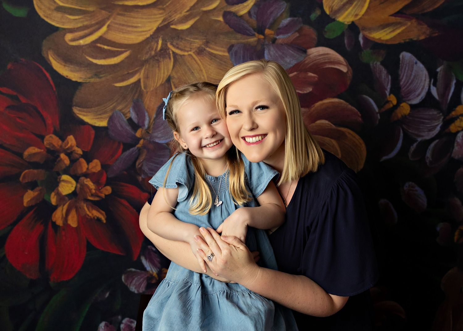 A loving portrait against a dark floral backdrop with vibrant orange and red painted flowers.