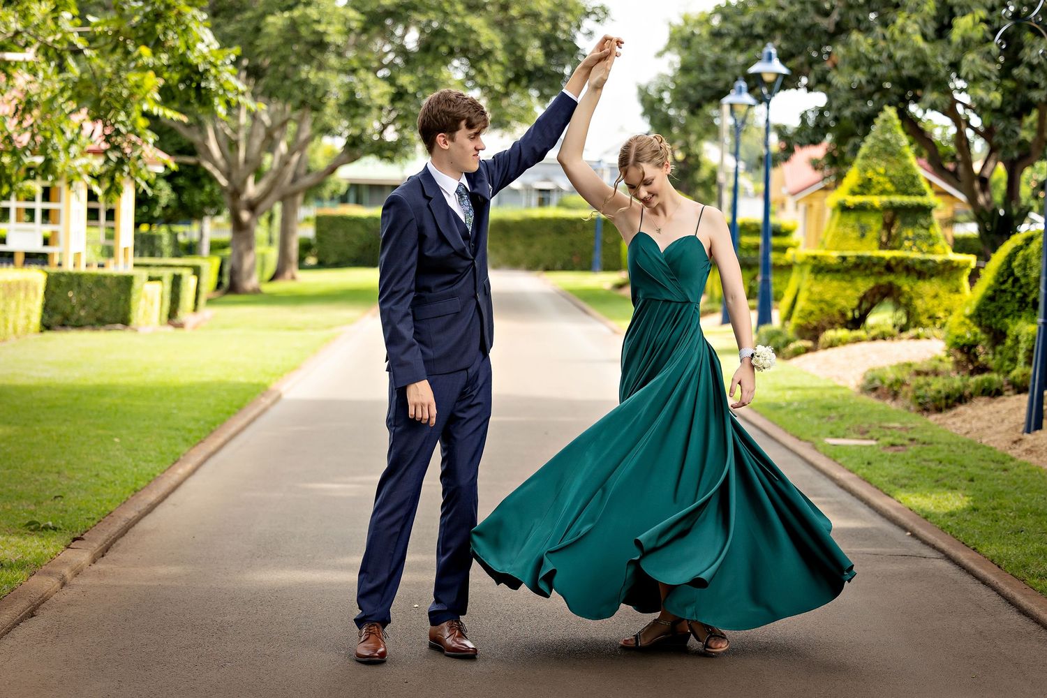 Couple in formal wear dance joyfully on garden pathway.Toowoomba Photographer Toowoomba Newborn Photographer