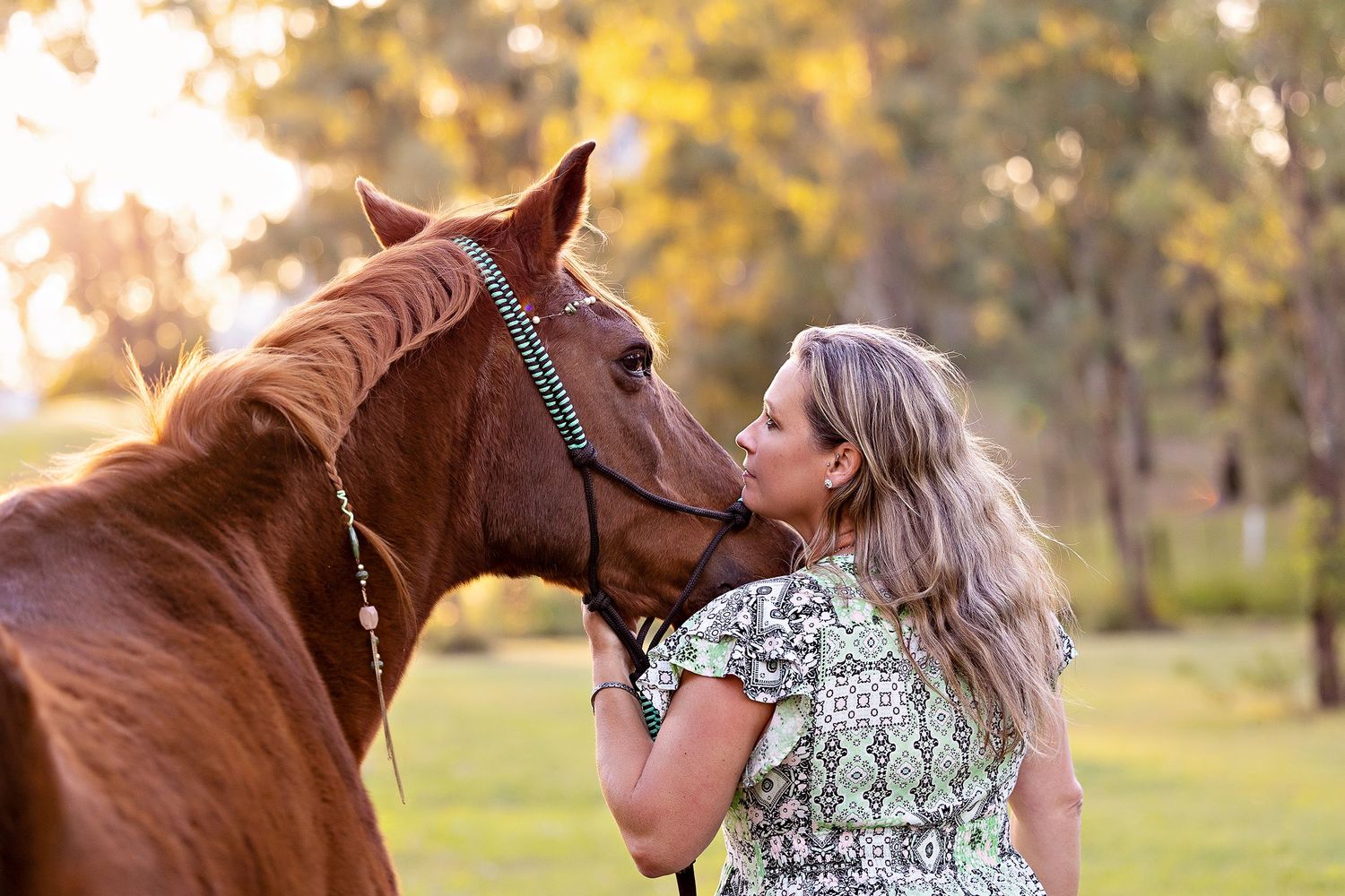 A chestnut horse and woman sharing an affectionate moment in a sunlit fieldToowoomba Photographer Toowoomba Newborn Photographer