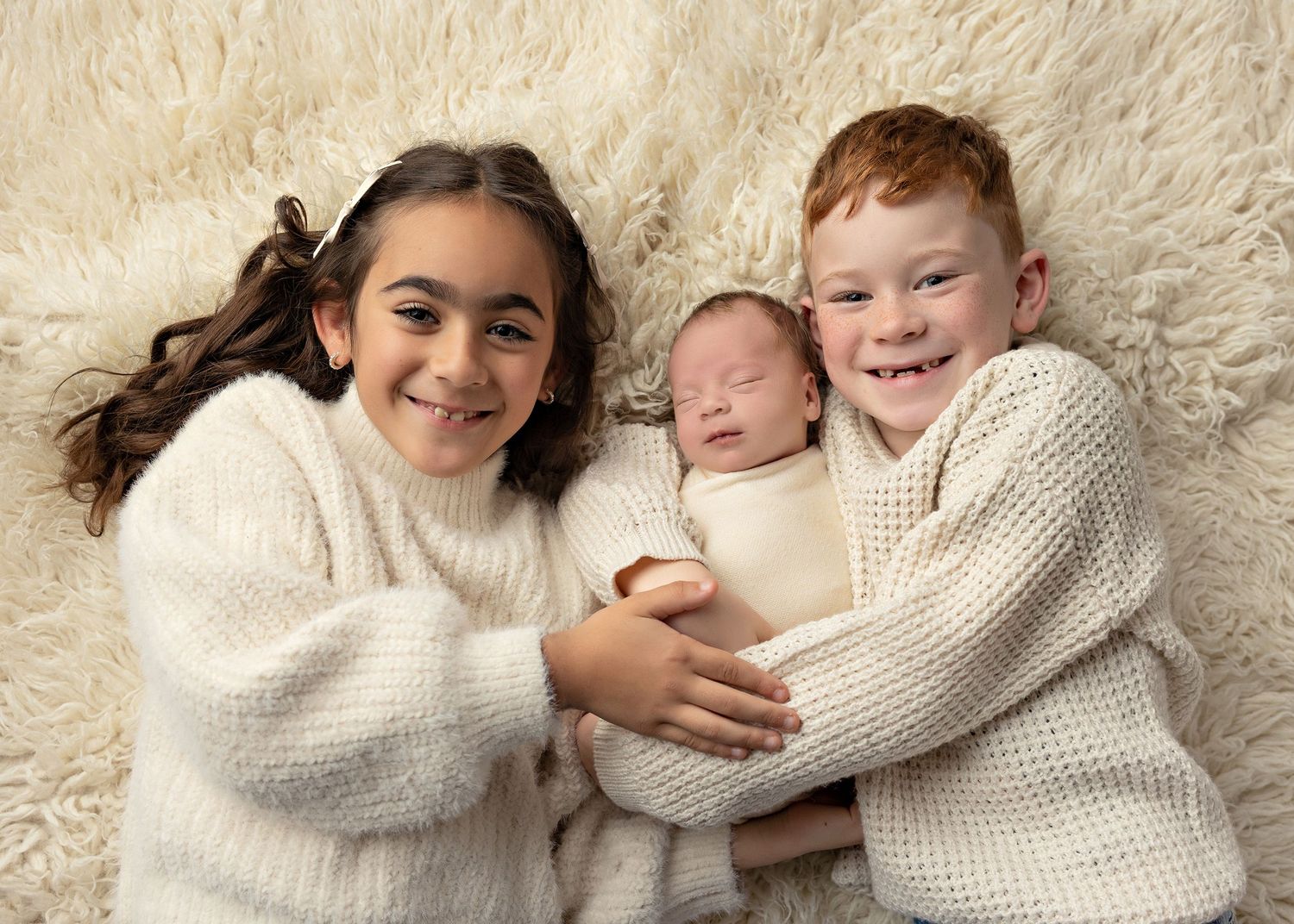 A series of intimate family photos showing tender moments between people in cozy white sweaters against a neutral background.