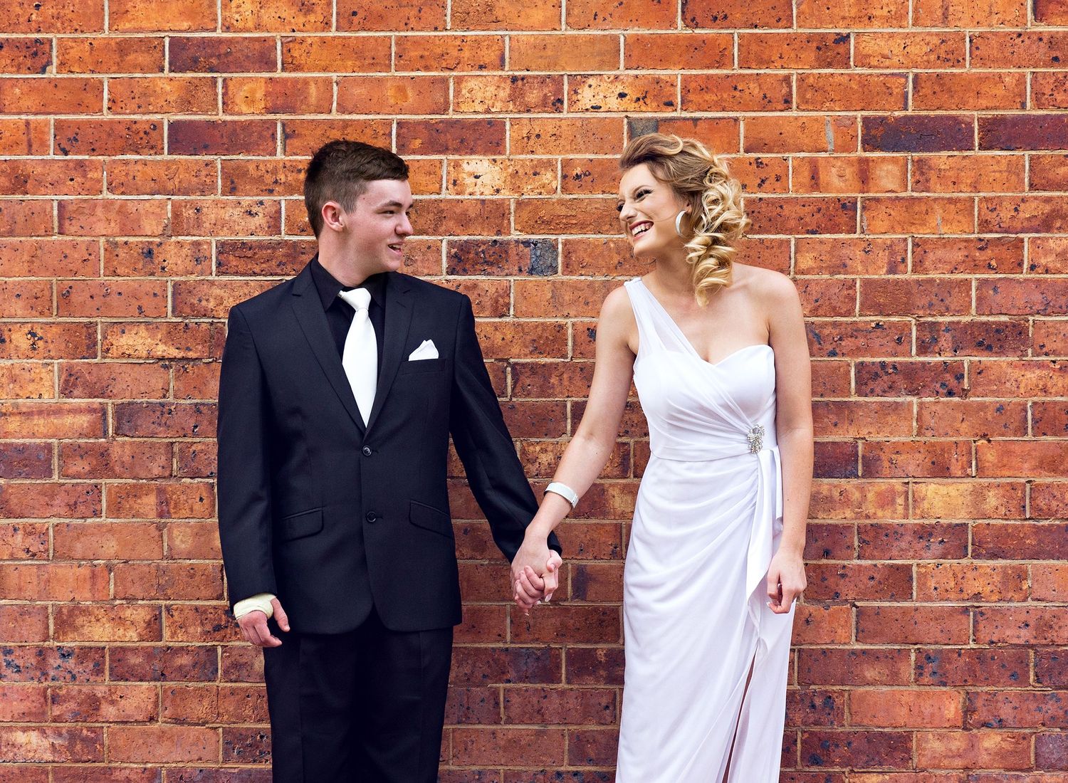 Wedding couple poses against rustic brick wall in formal attire.Toowoomba Photographer Toowoomba Newborn Photographer
