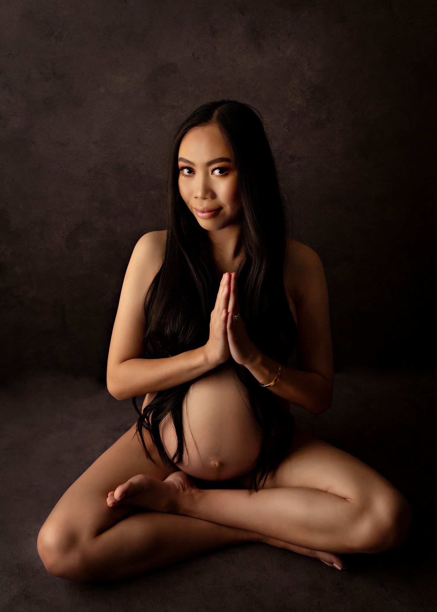 Maternity portrait of woman in yoga pose with hands in prayer position.