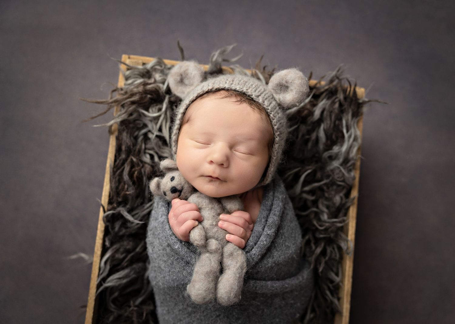 Newborn baby sleeping in grey knit wrap on textured dark backdrop with rustic propsToowoomba Photographer Toowoomba Newborn Photographer