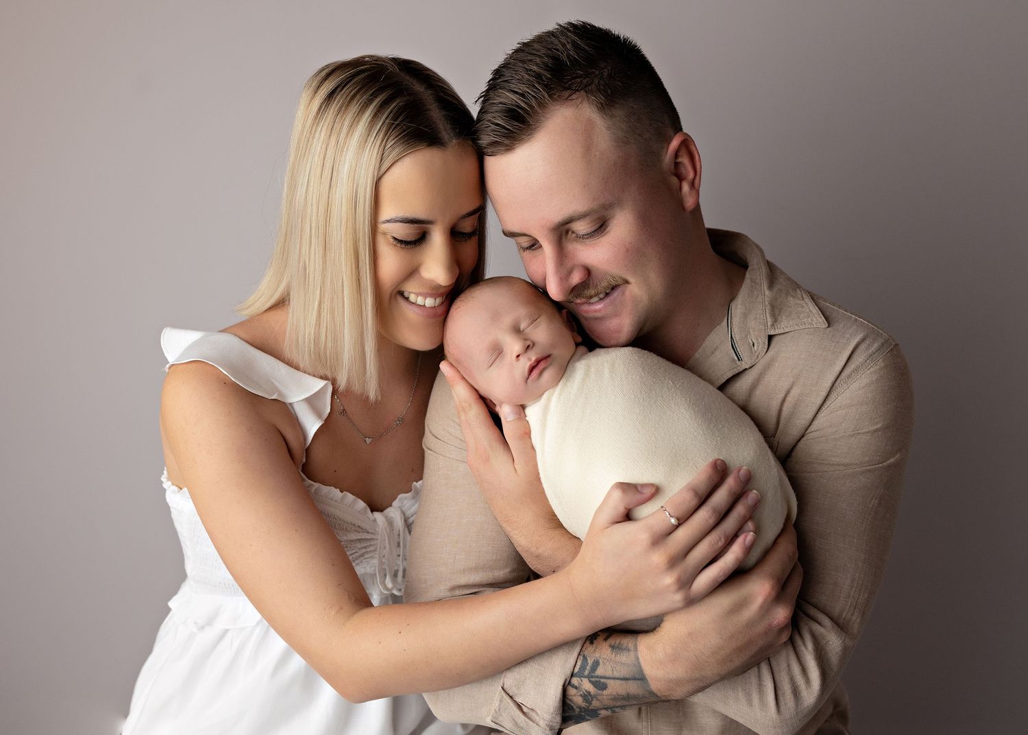 A series of intimate black and white family portraits showing tender moments with a newborn baby.