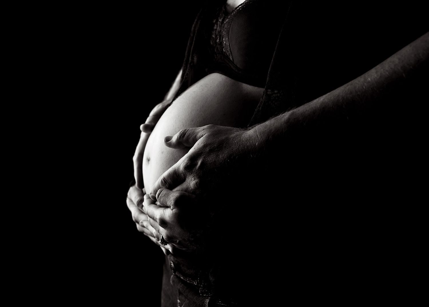 Black and white artistic photograph of a pregnant belly with hands cradling the bumpToowoomba Photographer Toowoomba Newborn Photographer