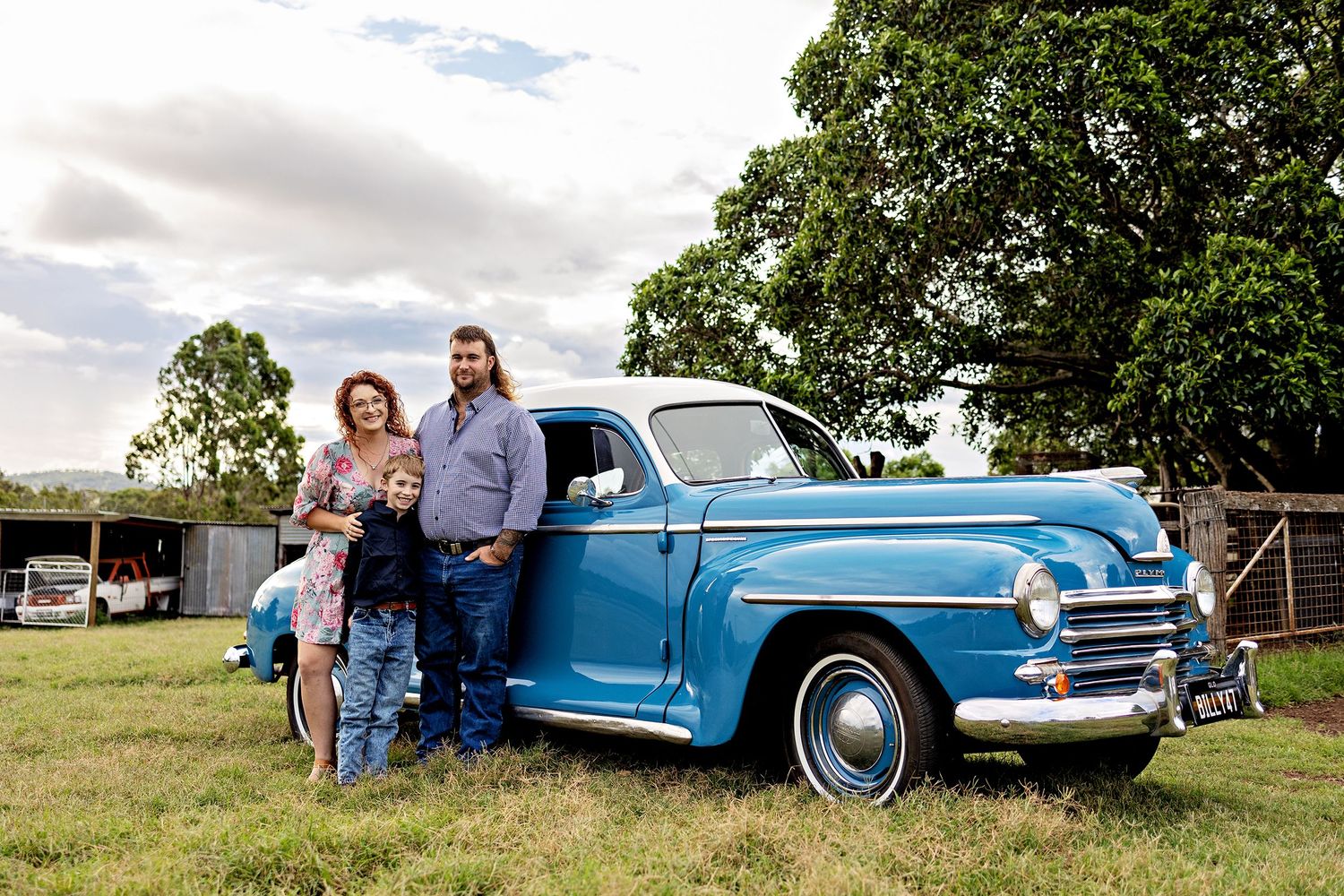 A classic blue vintage car parked on grass with trees in the backgroundToowoomba Photographer Toowoomba Newborn Photographer