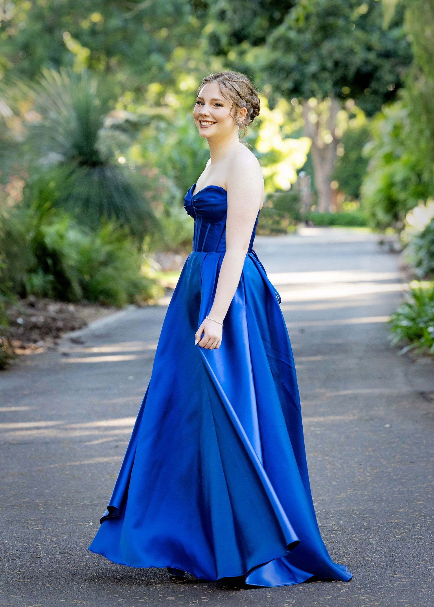 Person in flowing royal blue strapless gown stands on garden pathway.Toowoomba Photographer Toowoomba Newborn Photographer
