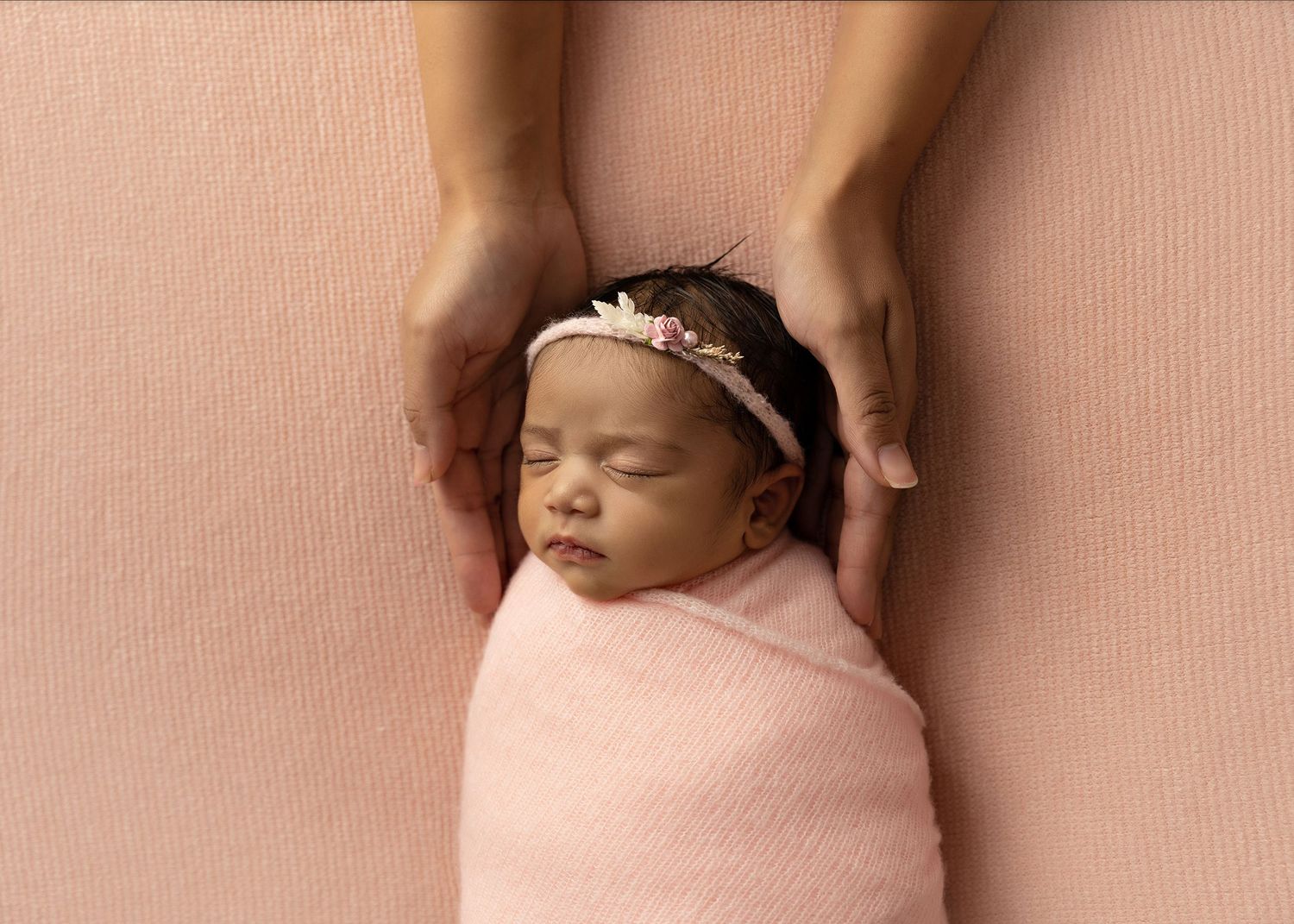 Newborn baby sleeping peacefully on pink background with delicate wrappingToowoomba Photographer Toowoomba Newborn Photographer