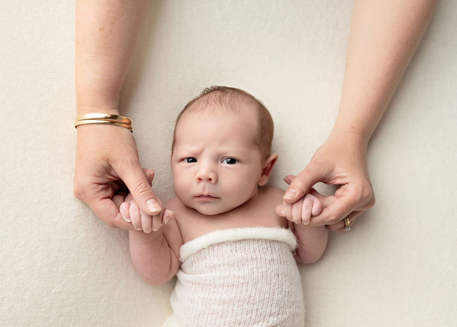 A series of close-up shots showing a newborn baby being wrapped in a soft white blanket.