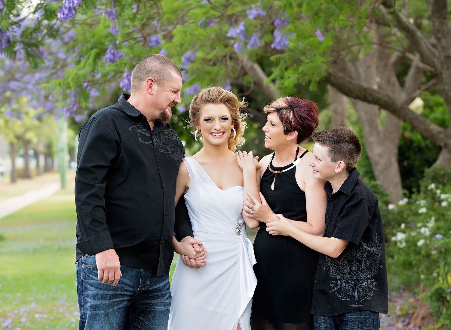 A family shares joyful moments together in a garden setting with lush greenery.Toowoomba Photographer Toowoomba Newborn Photographer