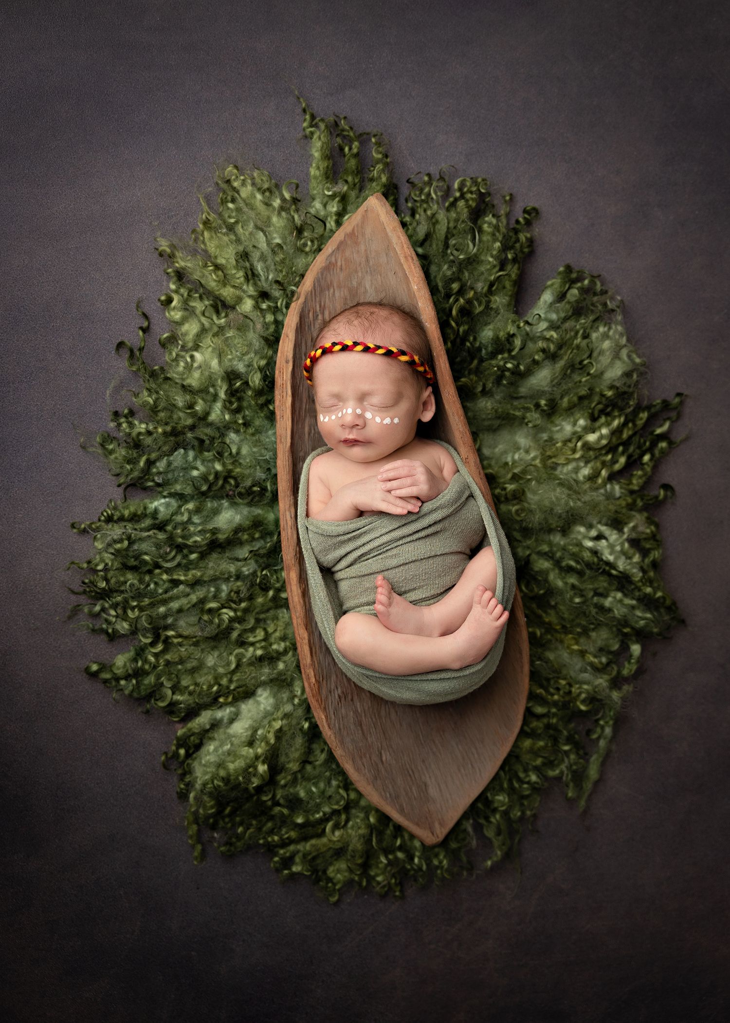 A series of newborn photography shots showing a sleeping baby in a wooden bowl surrounded by green foliage on dark backdrop.Toowoomba Photog