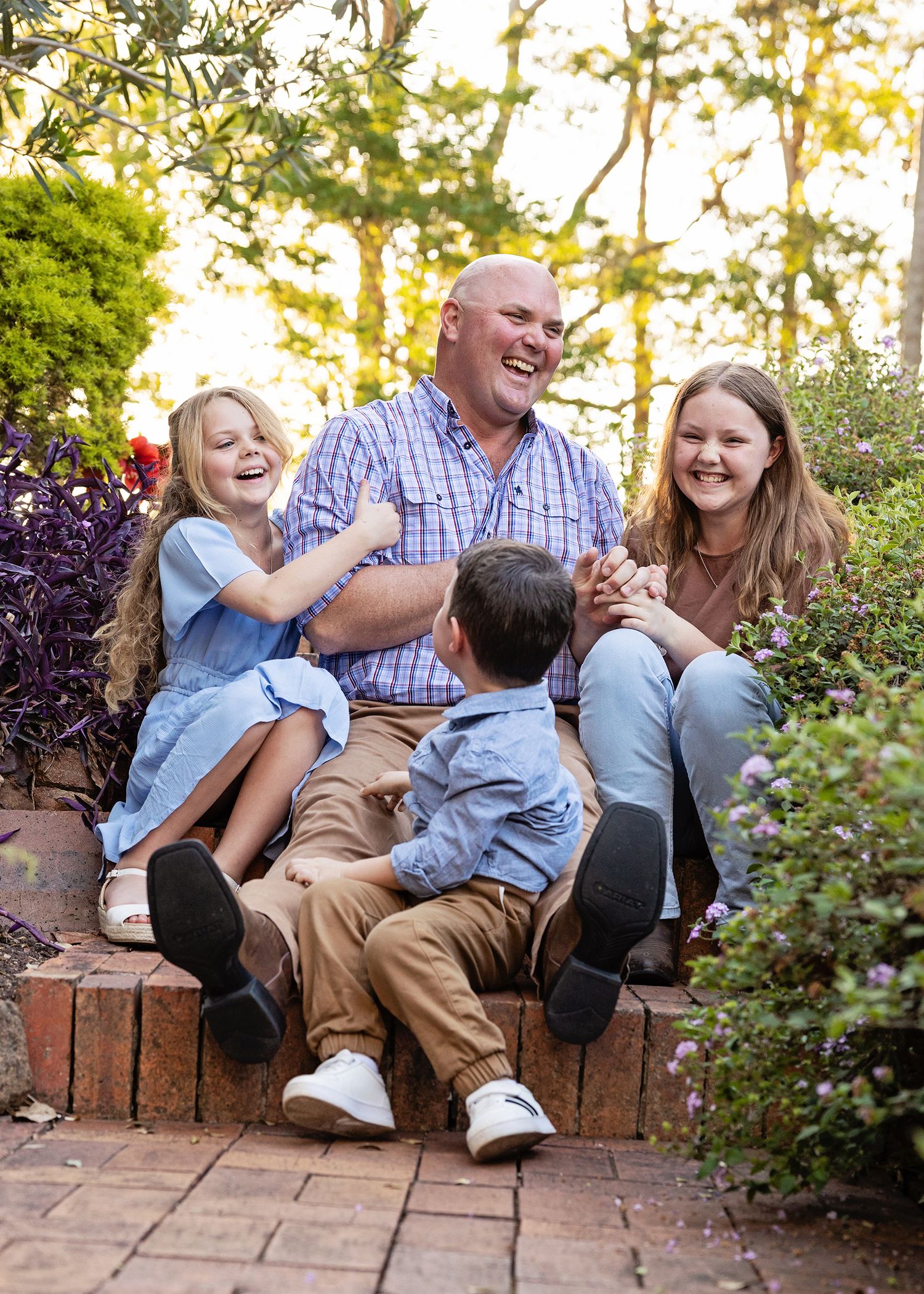 A joyful family moment captured on brick steps in a lush garden settingToowoomba Photographer Toowoomba Newborn Photographer