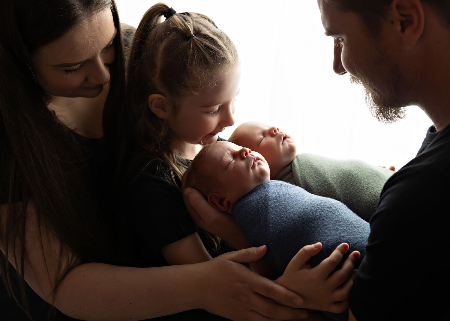 A family gathers close together in soft window light while bonding with their newborn baby.Toowoomba Photographer