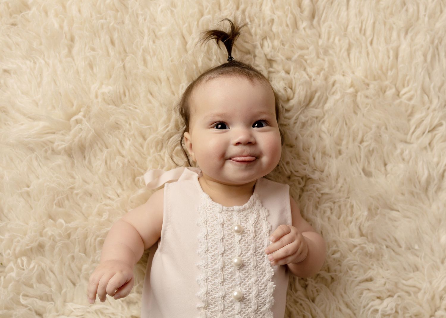 Baby photography session on cream colored fur rug wearing white lace outfit.Toowoomba Photographer Toowoomba Newborn Photographer