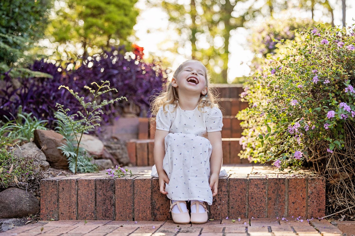 Brick steps in a lush garden surrounded by colorful blooming flowers and greenery.Toowoomba Photographer Toowoomba Newborn Photographer