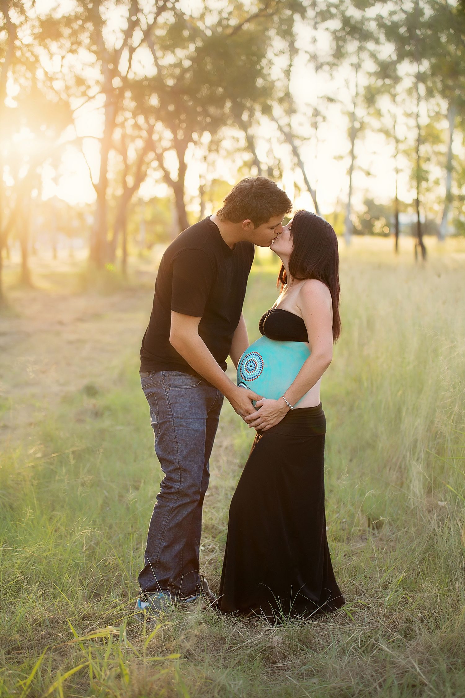 Intimate couple's portrait in tall grass during golden hour sunset.