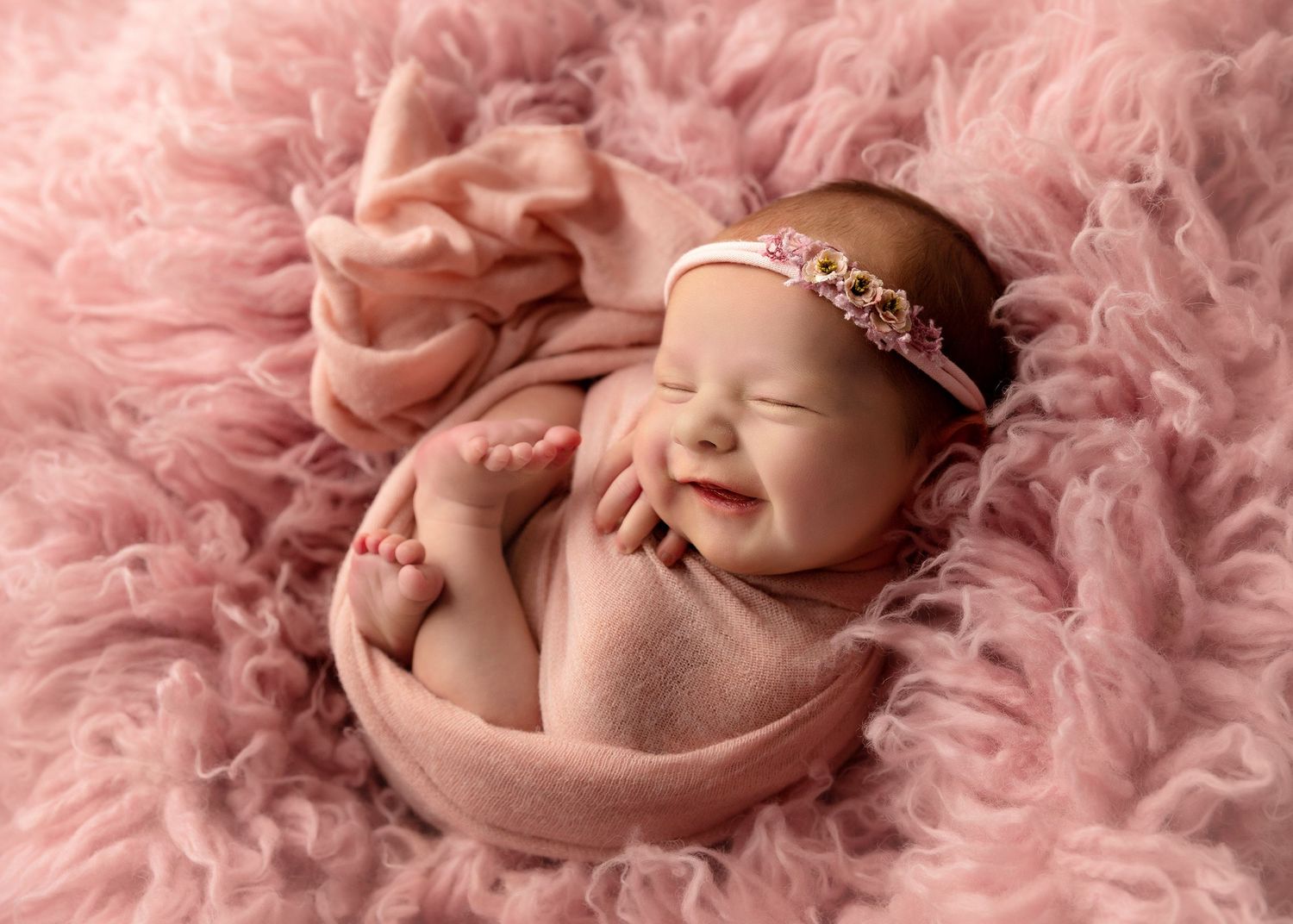 Sleeping newborn photographed on soft pink textured fabric with delicate lighting.Toowoomba Photographer Toowoomba Newborn Photographer