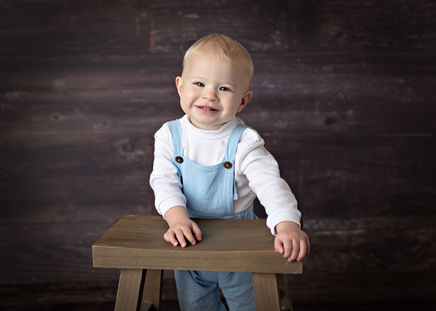 Collection of baby milestone photos showing growth and development against a dark wooden backdrop.