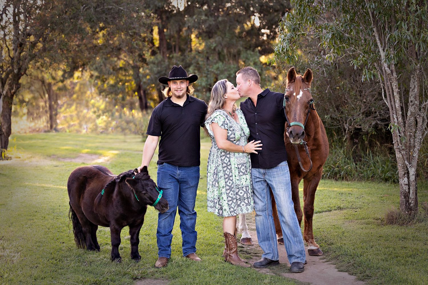A group gathered outdoors with horses and a miniature pony on a grassy pathToowoomba Photographer Toowoomba Newborn Photographer