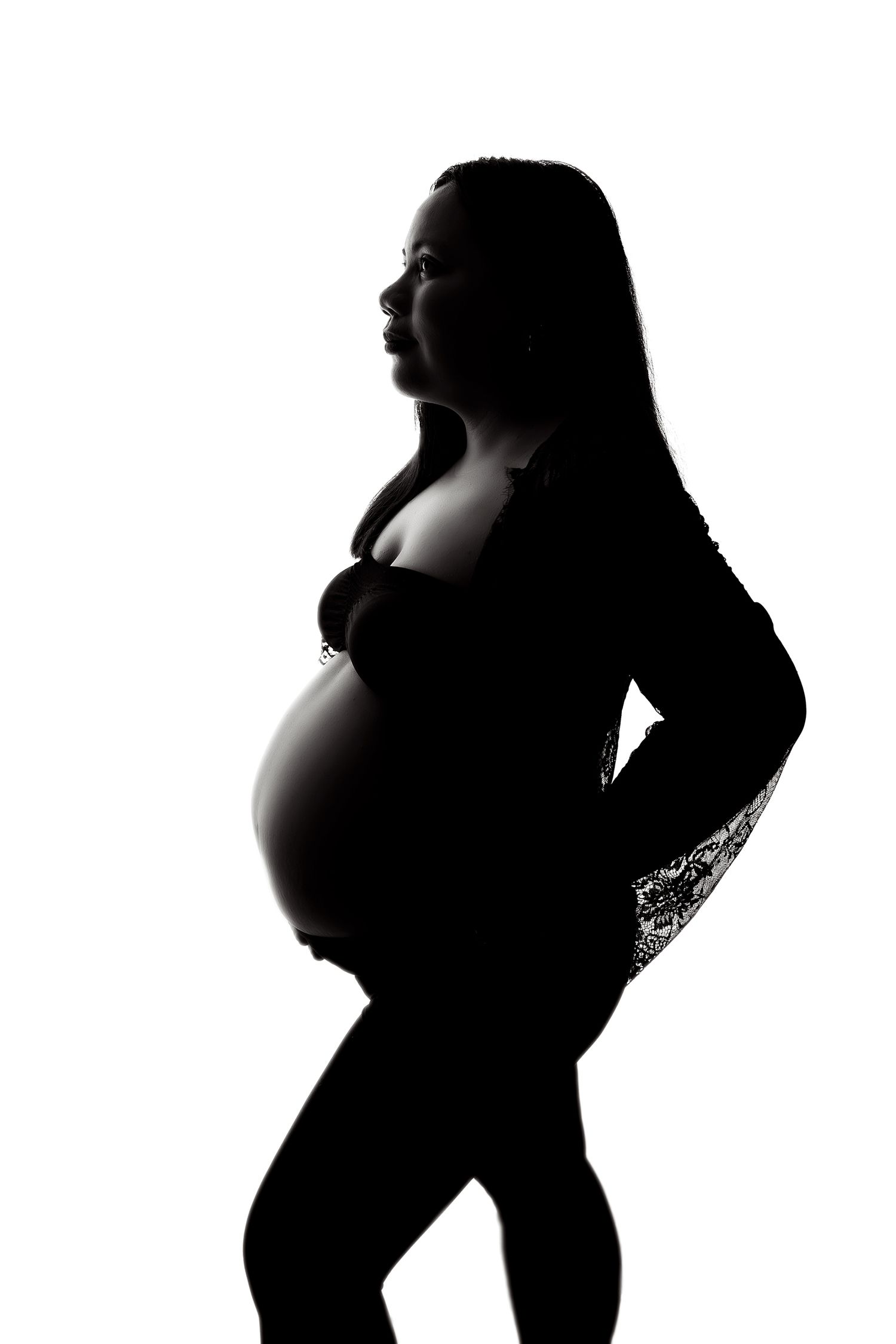Silhouette of a pregnant woman in profile against white background, showcasing her baby bump in black and white.