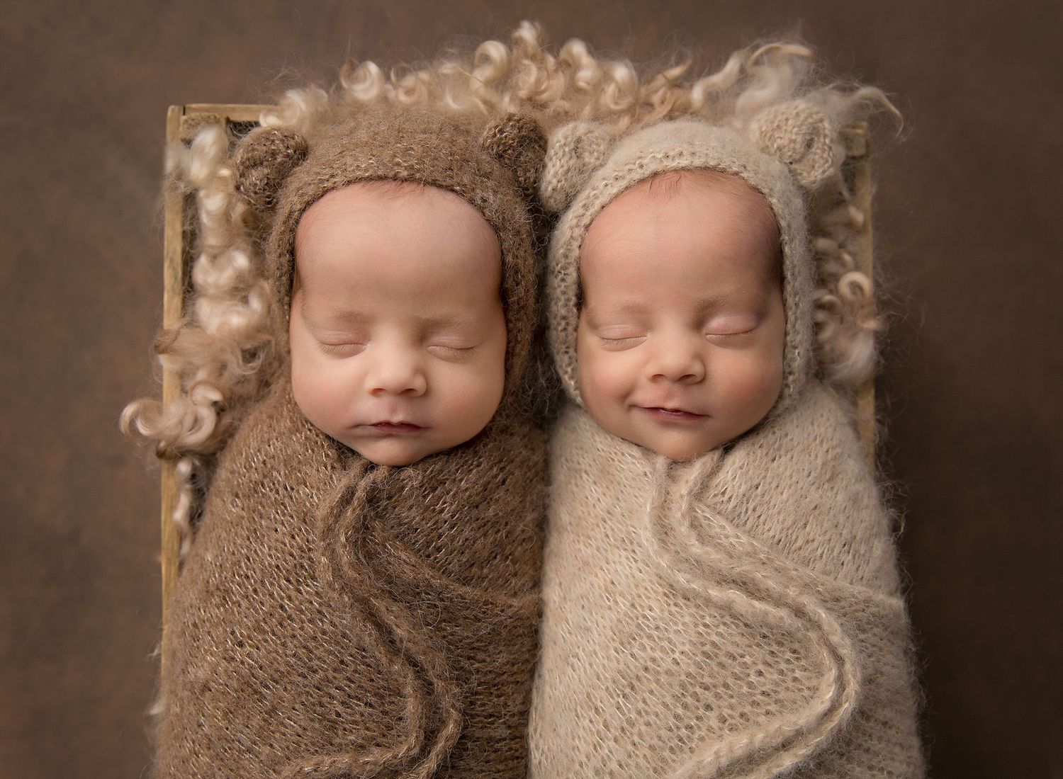 Two sleeping newborns wrapped in brown and beige knit blankets lie side by side in a professional portrait settingToowoomba Photographer