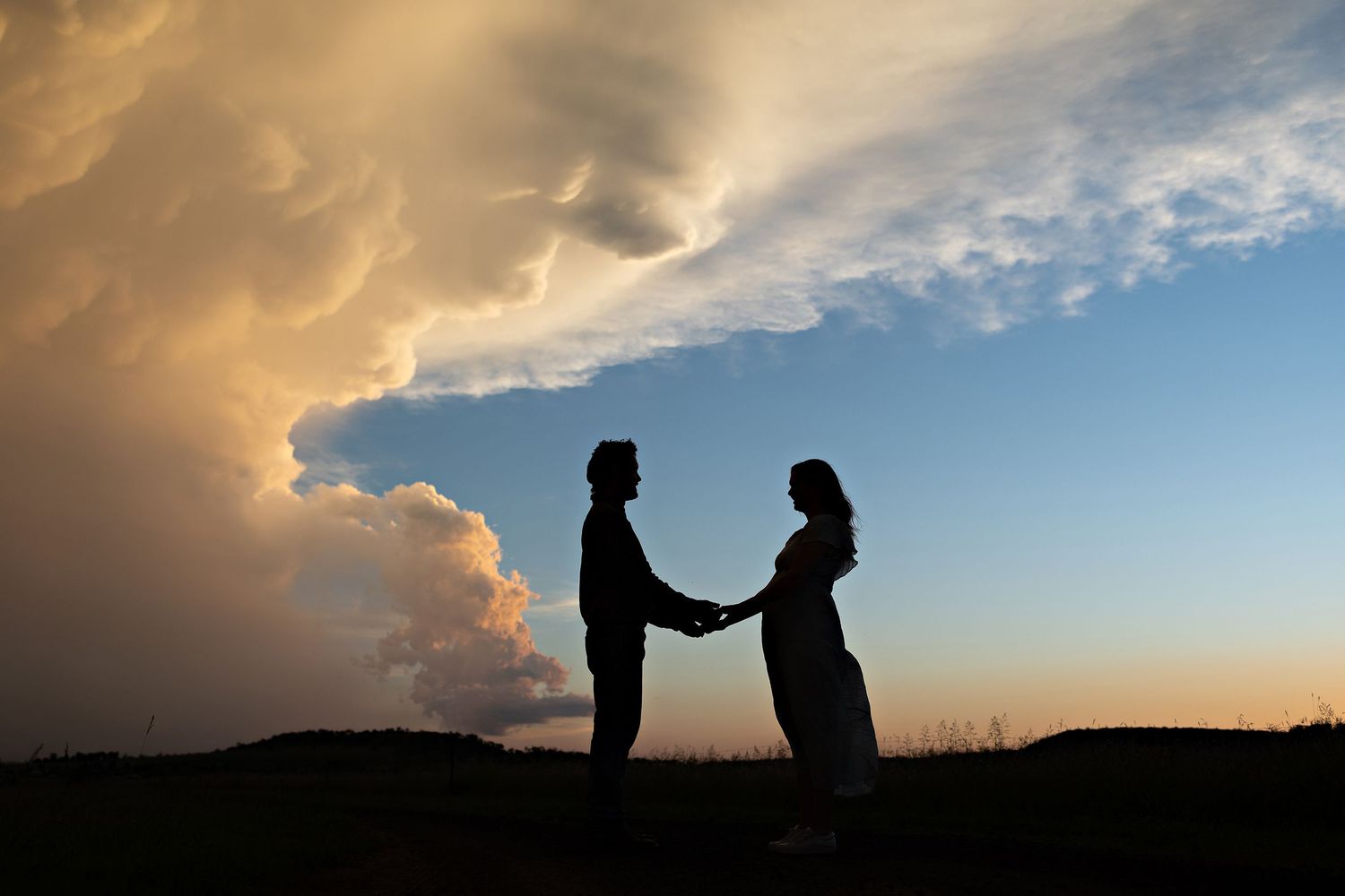 Dramatic sunset sky with silhouettes against orange and blue clouds.