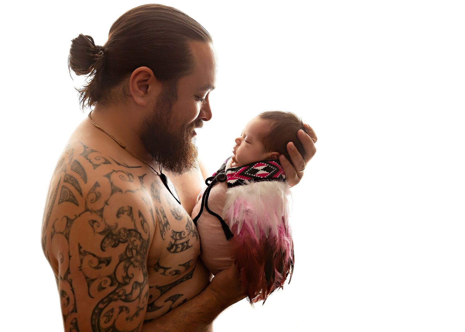 A tattooed person holds a small newborn baby against a white background.Toowoomba Photographer