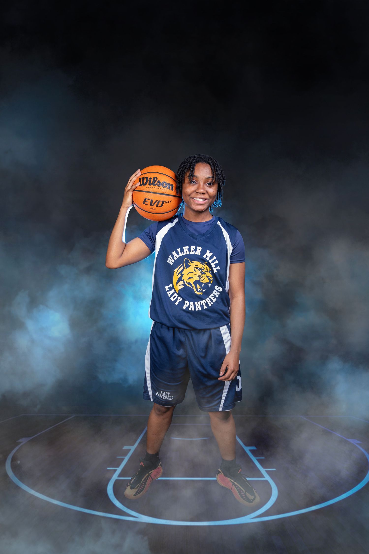 Smiling female athlete posing with Wilson basketball in Walker Mill Lady Panthers blue uniform.