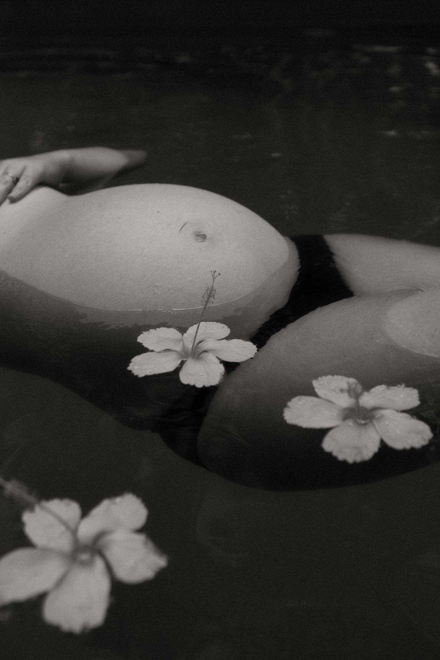 maternity woman floating in the pool with flowers