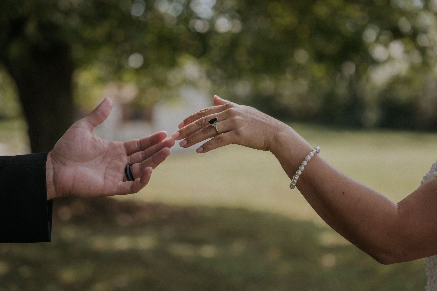 Hands reaching out to each other in a romantic outdoor wedding moment.