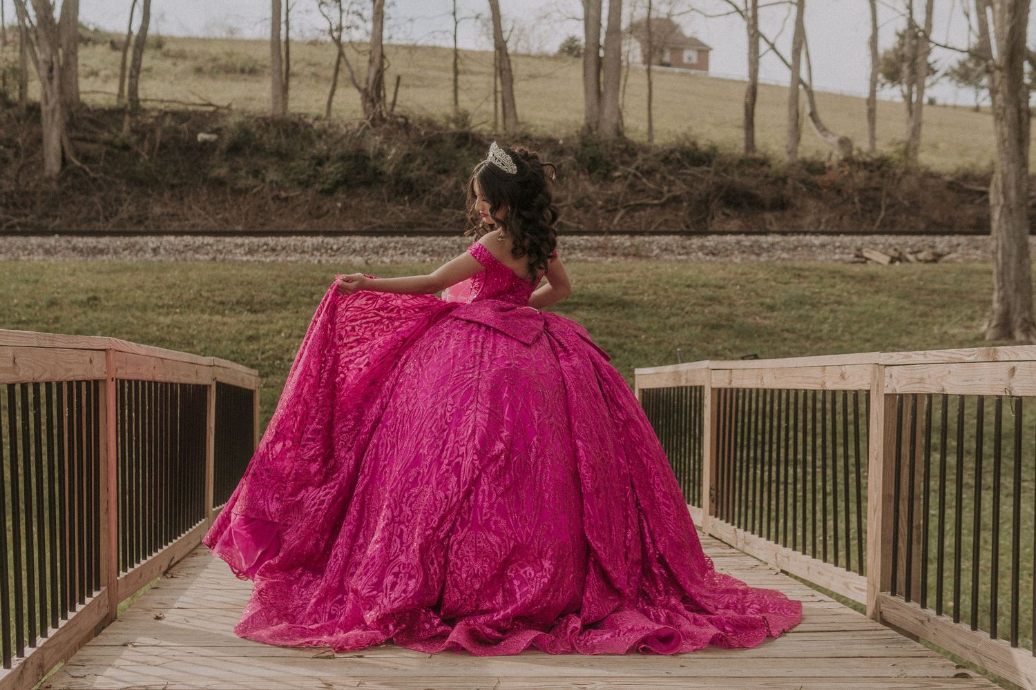 Vibrant magenta quinceañera dress photographed on an outdoor wooden deck.