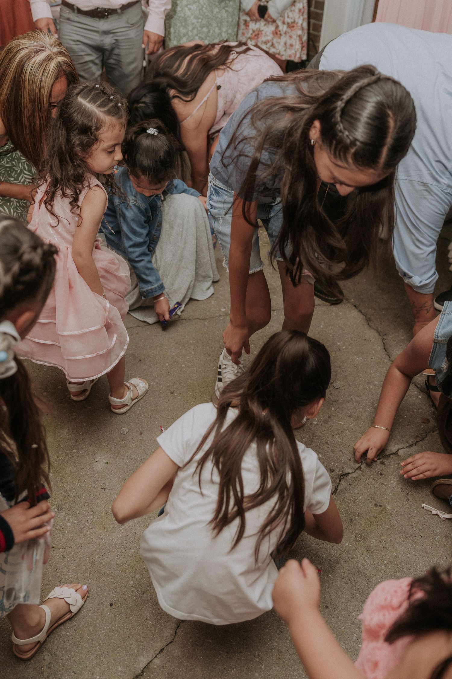 People crouch down to collect items from the ground during a baptism party game.