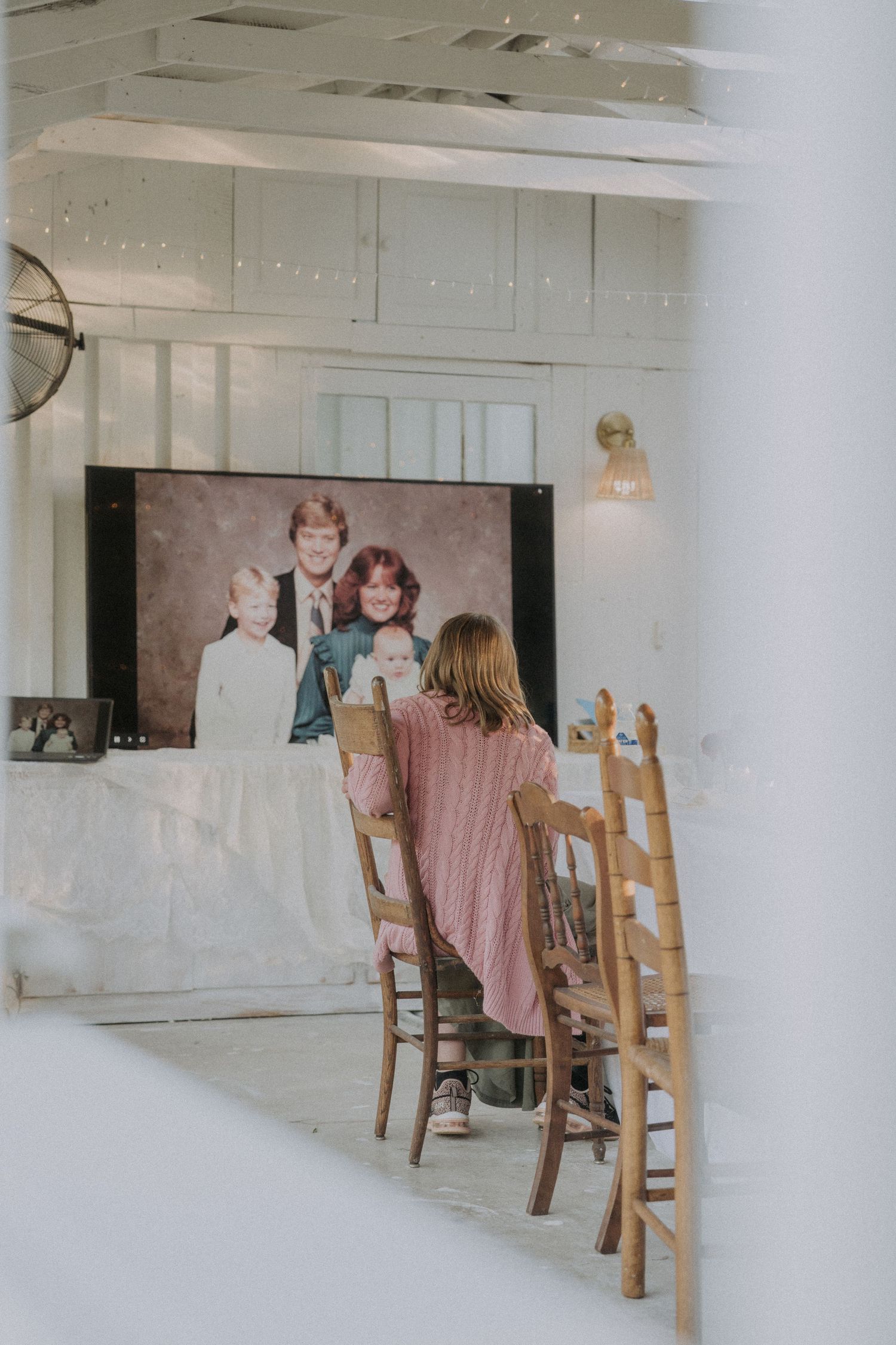 White interior room with wooden chairs and tables set up for an event.
