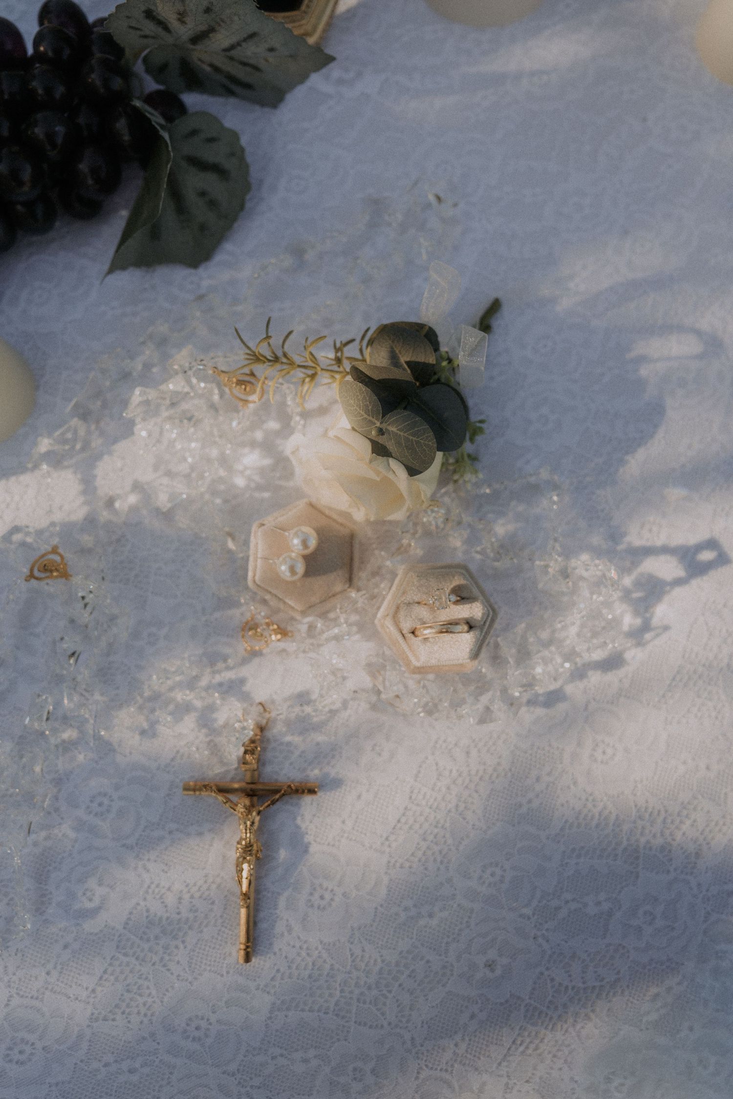 Religious jewelry and decorative wedding items arranged on a textured white surface.
