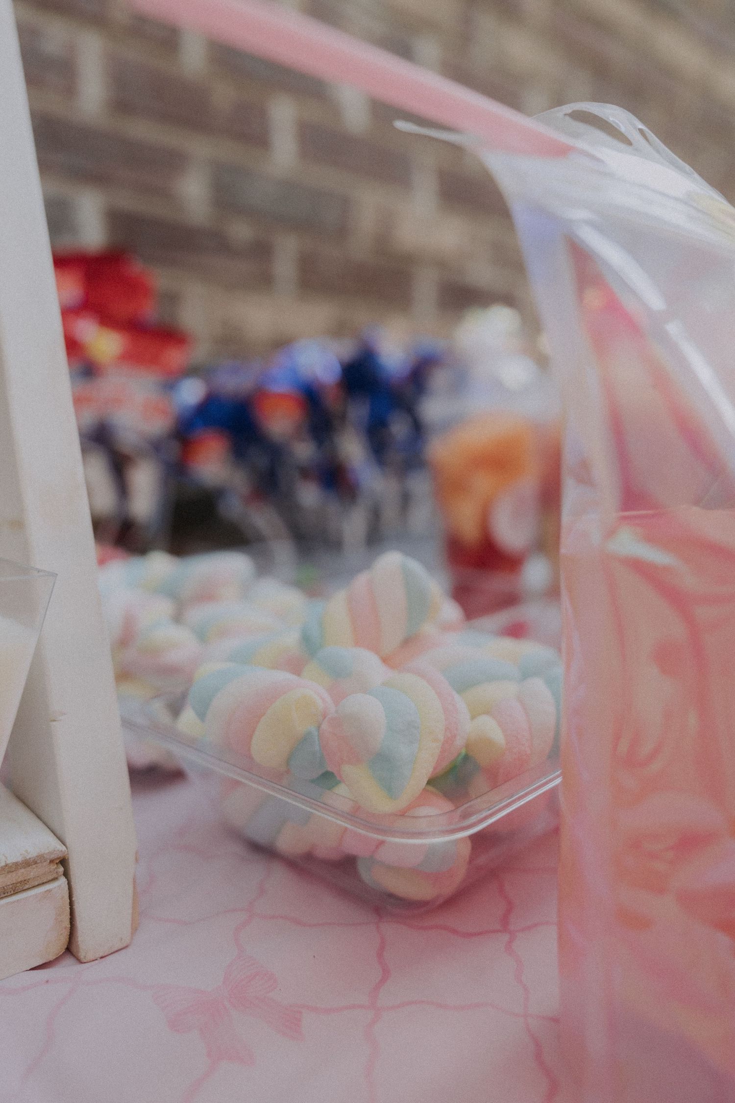 Pastel colored cotton candy arranged on a pink decorated table at a party.