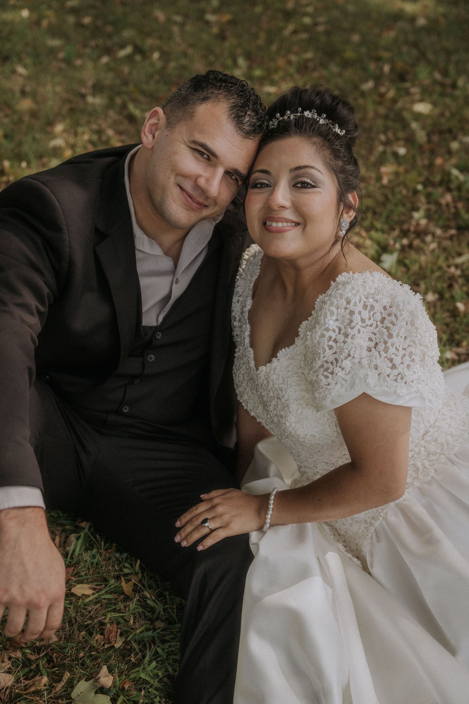 Couple in wedding attire sharing intimate moments on autumn grass.