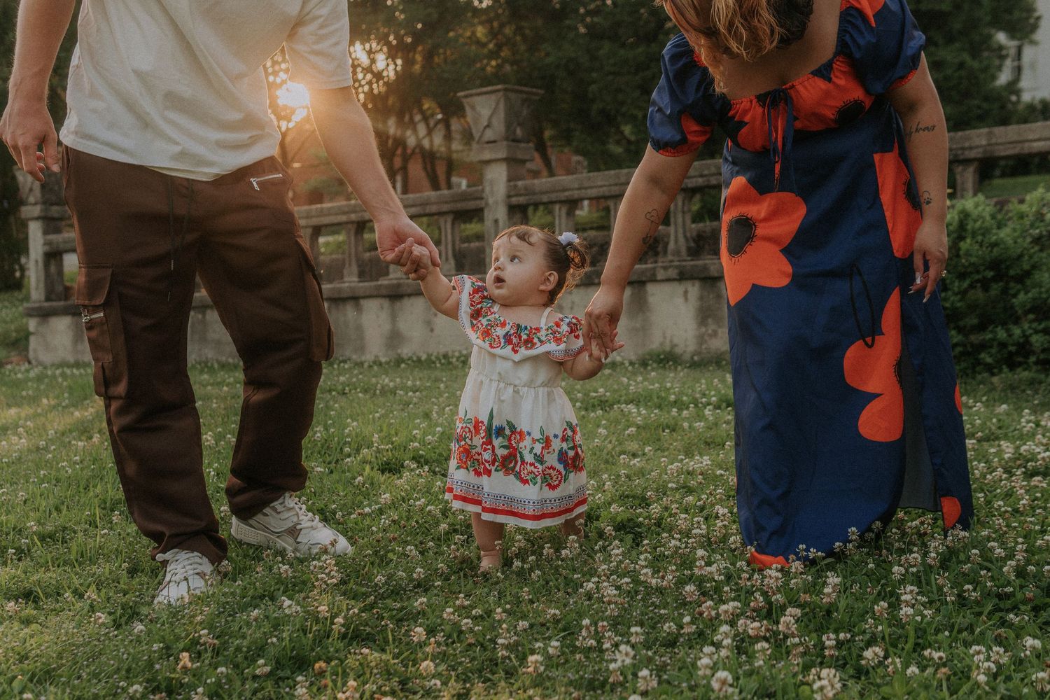 Candid moments of family walking in flowering meadow on spring evening.