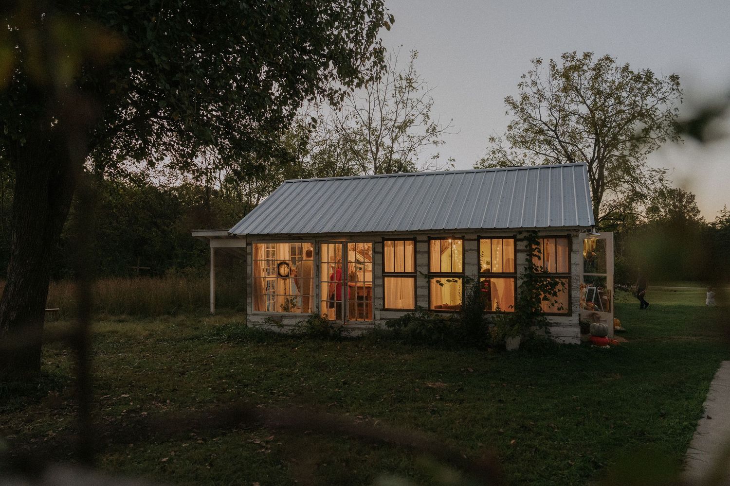 Modern ranch-style house with warm lighting at dusk creating a cozy atmosphere.