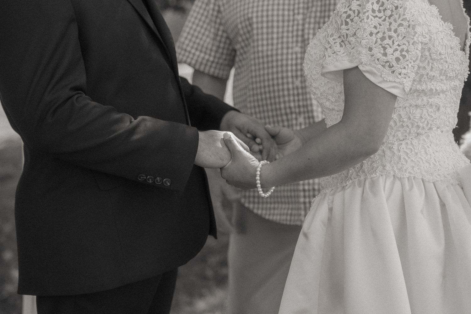 Close-up of wedding ring exchange during outdoor ceremony.