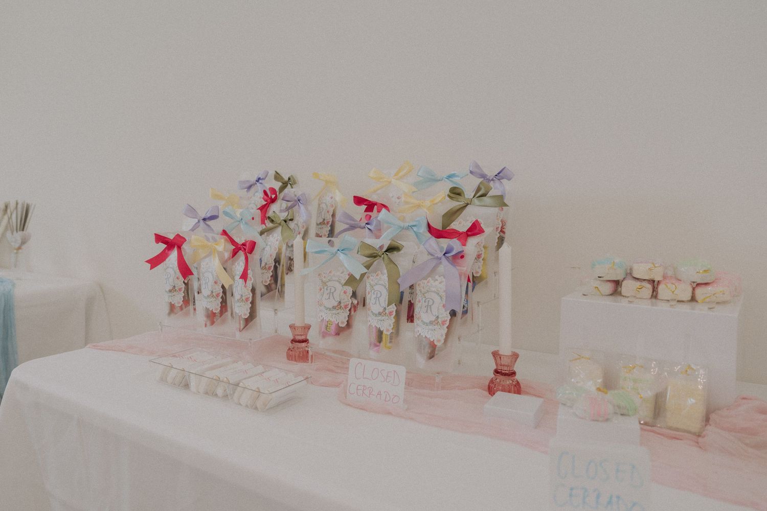 Elegant party favor table with colorful ribbon-tied gift bags and candles at a baby shower or wedding event.