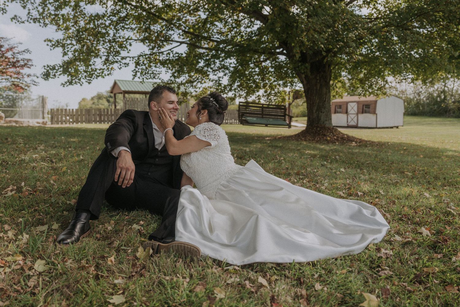 Couple relaxing together on grass during outdoor wedding photoshoot.