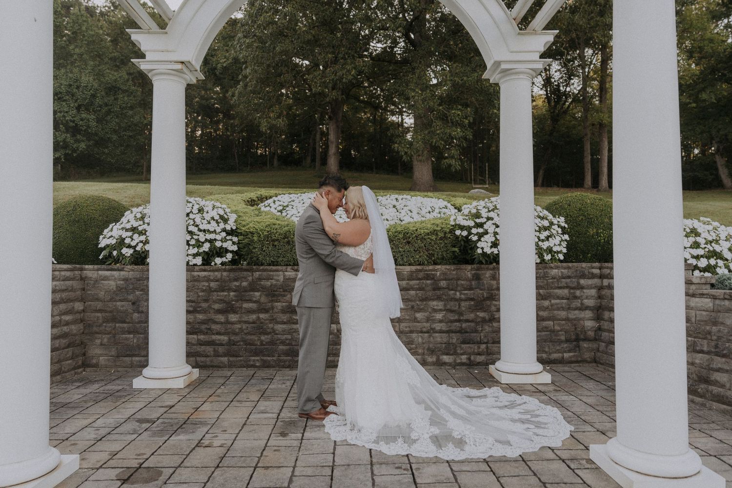 Wedding ceremony setup with white columned pergola and floral arrangements.